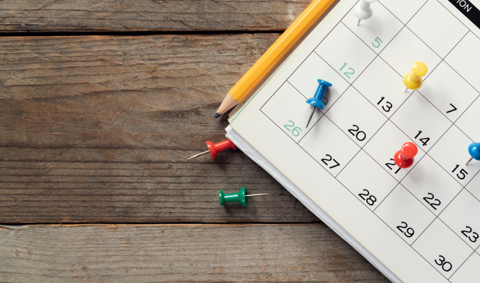 paper calendar with thumb tacks on a desk